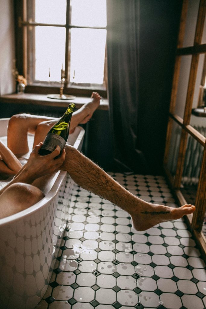 Cozy bathroom scene of a couple relaxing in a bathtub with champagne, capturing intimate leisure.
