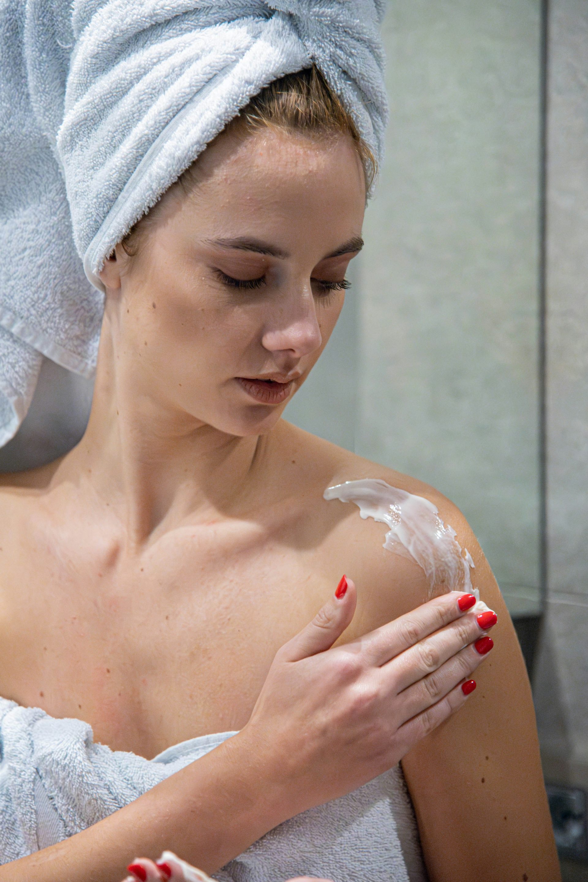 une femme avec une serviette sur la tête se rase le visage